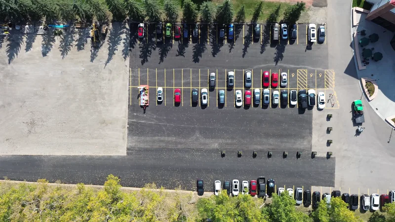 Straight-down aerial of a finished, line-painted commercial parking lot in Calgary with cars parked
