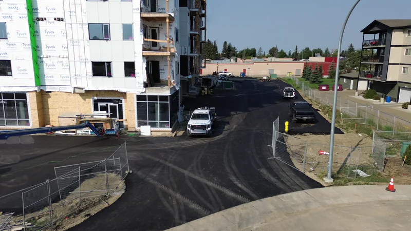 Finished asphalt parking lot and drive lane at the corner of a new apartment building in Olds